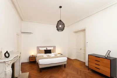 a white bedroom with a bed and a dresser at La Pittoresque 1 in Carcassonne