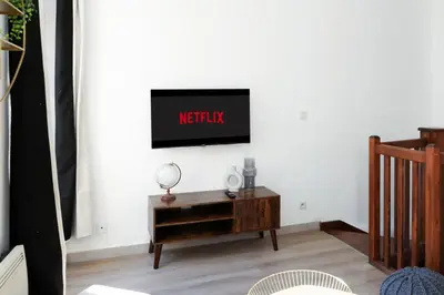 a living room with a tv on a white wall at N1 Des Études Cosy Duplex Netflix Balcon ConciergerieDameCarcas in Carcassonne