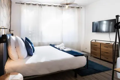 a bedroom with a large white bed with blue pillows at N1 Des Études Cosy Duplex Netflix Balcon ConciergerieDameCarcas in Carcassonne