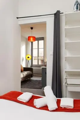 a bedroom with a bed and a living room at N2 des Études Cosy Hypercentre Wifi ConciergerieDameCarcas in Carcassonne