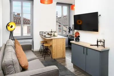 a living room with a couch and a kitchen at N2 des Études Cosy Hypercentre Wifi ConciergerieDameCarcas in Carcassonne