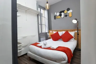 a bedroom with a large bed with red pillows at N2 des Études Cosy Hypercentre Wifi ConciergerieDameCarcas in Carcassonne