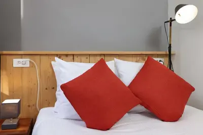 a bed with red and white pillows and a lamp at N2 des Études Cosy Hypercentre Wifi ConciergerieDameCarcas in Carcassonne