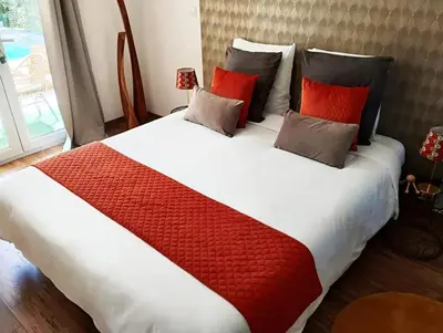 a large bed with red and white sheets and pillows at Le Mas Victoria - Chambres d'hôtes avec table d'hôtes-Parking privé ferme in Carcassonne