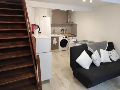 a living room with a couch and a kitchen at T2 Duplex Pamiers Plein Centre - Logement entier - Nouveau in Pamiers