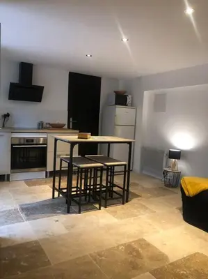 a kitchen with a table and some chairs in it at Bienvenue « À l’ombre du figuier » in Pieusse