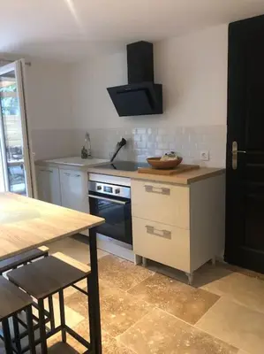 a kitchen with a table and a stove top oven at Bienvenue « À l’ombre du figuier » in Pieusse