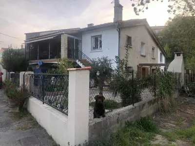 a dog sitting on a fence in front of a house at Bienvenue « À l’ombre du figuier » in Pieusse