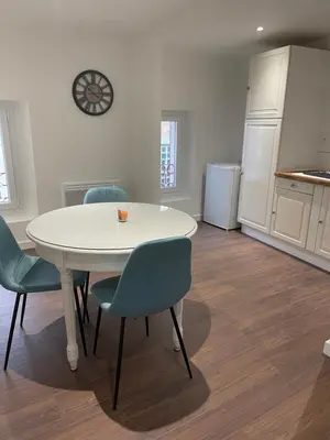 a kitchen with a white table and chairs and a kitchen with a refrigerator at Les Appartements du Cep’t in Mazamet