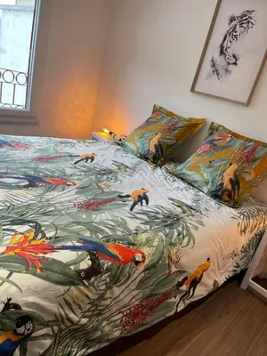 a bed with a colorful blanket with fish on it at Les Appartements du Cep’t in Mazamet