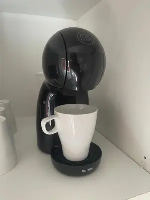 a coffee maker with a cup on a counter at Les Appartements du Cep’t in Mazamet