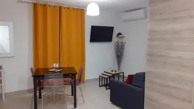 a living room with a table and a yellow curtain at L'Ancestrale, Beau T2 in Limoux