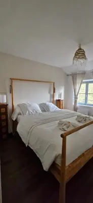 a bedroom with a large bed with white sheets and a window at La Robine in Narbonne