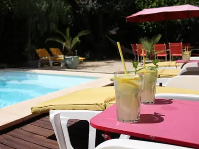 two drinks on a pink table next to a pool at La maison des Vendangeurs 10 in Olonzac