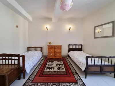 a bedroom with two beds and a dresser and a rug at La maison des Vendangeurs 10 in Olonzac