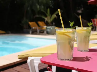 two drinks on a pink table next to a swimming pool at La maison des Vendangeurs 10 in Olonzac