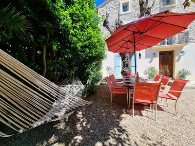 a hammock and a table and chairs under a red umbrella at La maison des Vendangeurs 10 in Olonzac