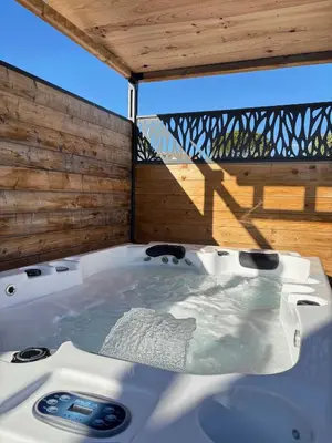 a jacuzzi tub in a room with a balcony at Gîte & Spa Le Villemachois - 4 étoiles - Jacuzzi couvert - Calme et Indépendant - Clim - Parking - 5 min Carcassonne in Villemoustaussou