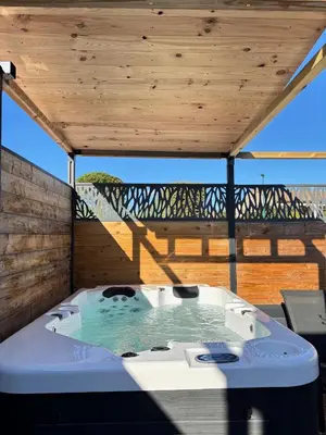 a hot tub on a deck with a wooden roof at Gîte & Spa Le Villemachois - 4 étoiles - Jacuzzi couvert - Calme et Indépendant - Clim - Parking - 5 min Carcassonne in Villemoustaussou