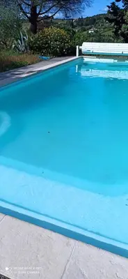 a swimming pool with blue water in a yard at Le Rocher au Thym in Limoux
