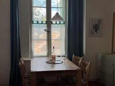 a dining room table with a bottle of wine and a window at Maison de l´amitié Homps in Homps
