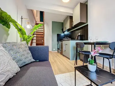 a living room with a couch and a table and a kitchen at Solstice T2 Hypercentre SmartTV Wifi in Pamiers
