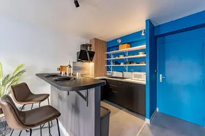 a kitchen with blue walls and a bar with stools at Solstice T2 Hypercentre SmartTV Wifi in Pamiers