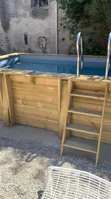 a wooden deck with a ladder next to a swimming pool at Cosy Camon Bolt-Hole in Camon