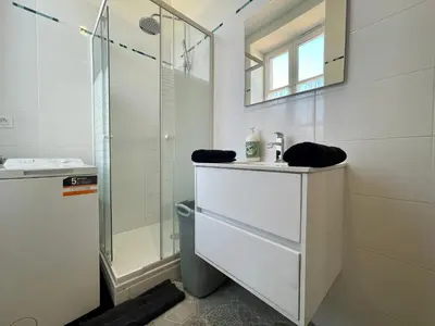 a white bathroom with a sink and a shower at Les appartements d'Arthur - Pont-Neuf in Carcassonne