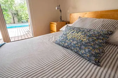 a bedroom with a bed with a pillow and a window at Belle villa moderne 3 chambres, jardins terrasse piscine in Durban-Corbières
