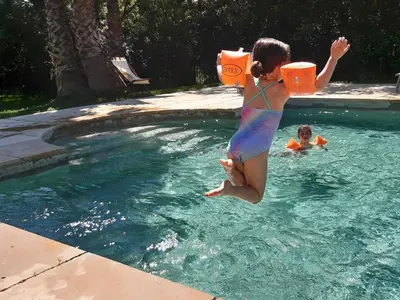 a woman jumping into a swimming pool at Domaine de Livière-Haute Narbonne in Narbonne