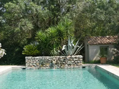 a swimming pool with a stone wall next to a yard at Domaine de Livière-Haute Narbonne in Narbonne