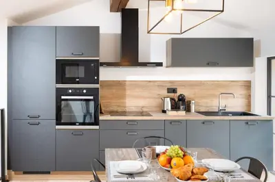 a kitchen with gray cabinets and a table with fruit on it at Longue Vie Au Roi - Vue Enchanteresse in Carcassonne