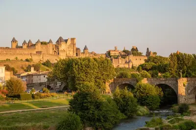 a view of a castle and a river with a bridge at Le Manoir d'Amiel a secret 16 bedroom garden oasis for groups up to 30 in Villegailhenc