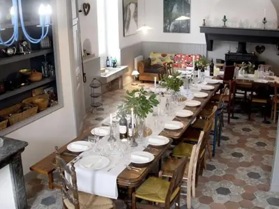 a patio with chairs and tables under a tree at Le Manoir d'Amiel a secret 16 bedroom garden oasis for groups up to 30 in Villegailhenc