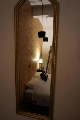 a mirror in a room with a bed and a lamp at Le 100 in Carcassonne