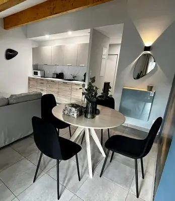 a living room with a table and chairs and a kitchen at Les Demoiselles de la Tour ! in Carcassonne