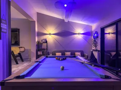 a pool table in a living room with purple lighting at Carcalove - Pool, Billard & Jacuzzi - 10pax in Fontiès-dʼAude
