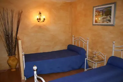 a bedroom with a blue bed and a chandelier at Domaine du coude in Saint-André-de-Roquelongue