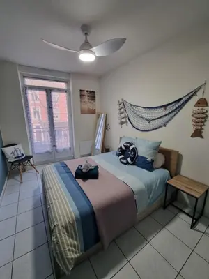 a bedroom with a bed with a ceiling fan at La cabane bleue à Narbonne in Narbonne
