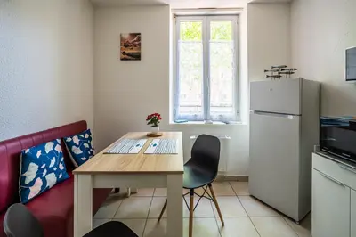 a small kitchen with a table and a refrigerator at La cabane bleue à Narbonne in Narbonne