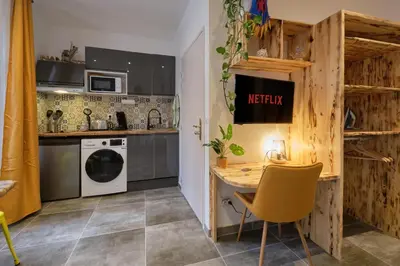 a small kitchen with a table and a yellow chair at Place Carnot - studio tout équipé avec jacuzzi proche toutes commodités in Carcassonne