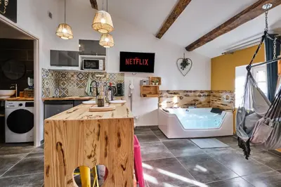 a kitchen with a wooden table and a bath tub at Place Carnot - studio tout équipé avec jacuzzi proche toutes commodités in Carcassonne