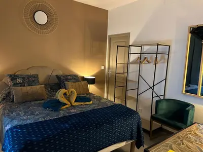 a bedroom with a bed and a green chair at La CORSA CHAMBRE FAMILIALE DELUXE in Narbonne