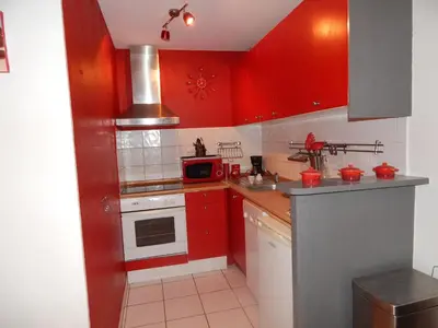 a red kitchen with red cabinets and a microwave at Villa à 50 m de la plage du Grazel pour 6 personnes in Gruissan