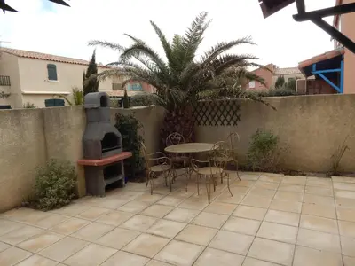 a patio with a table and chairs and a stove at Villa à 50 m de la plage du Grazel pour 6 personnes in Gruissan