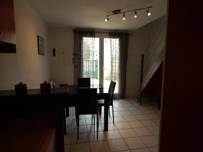 a dining room with a table and chairs and a staircase at Villa à 50 m de la plage du Grazel pour 6 personnes in Gruissan