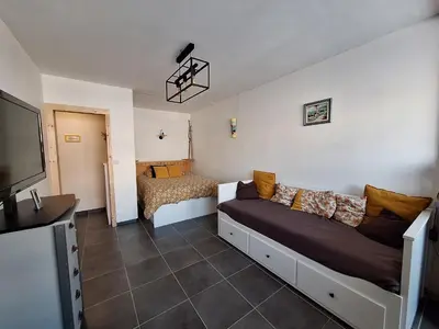 a room with a couch and a bed and a television at Chaleureux studio en bord de mer in Port-la-Nouvelle