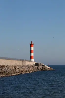 a red and white lighthouse sitting on the edge of the water at Chaleureux studio en bord de mer in Port-la-Nouvelle