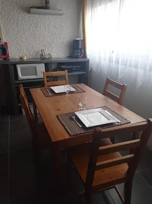 a wooden table with chairs and a plate on it at Chaleureux studio en bord de mer in Port-la-Nouvelle